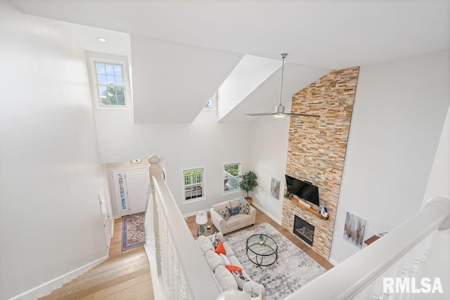1100 Wild W Dr, Le Claire, IA 52753 - living area featuring light wood-style floors, high vaulted ceiling, a stone fireplace, and ceiling fan