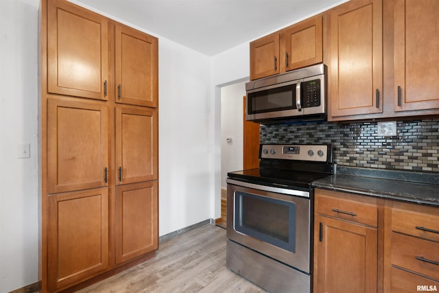 612 Waverly Rd, Davenport, IA 52804 - kitchen with appliances with stainless steel finishes, light wood-style flooring, brown cabinetry, backsplash, and dark stone counters