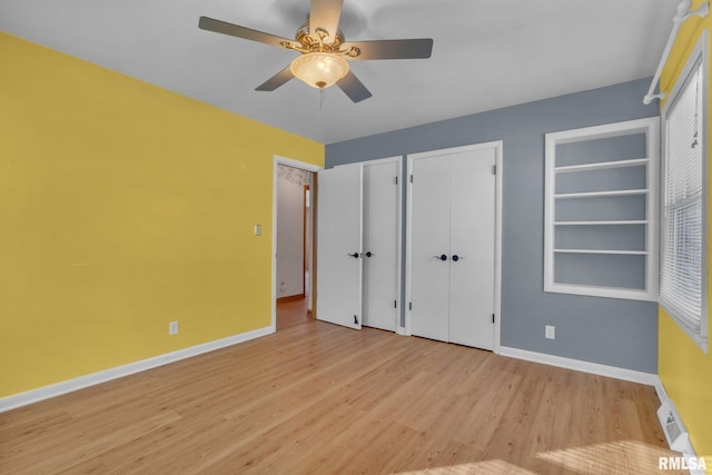 206 E 13th St, Tipton, IA 52772 - unfurnished bedroom featuring wood finished floors, multiple closets, and a ceiling fan