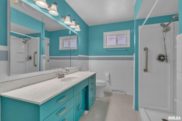 206 E 13th St, Tipton, IA 52772 - full bath featuring a shower stall, wainscoting, vanity, and tile walls
