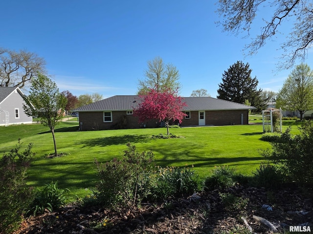 206 E 13th St, Tipton, IA 52772 - back of property featuring a yard, a metal roof, and brick siding