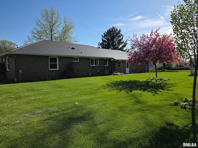 206 E 13th St, Tipton, IA 52772 - back of house featuring a lawn, brick siding, a metal roof, and a standing seam roof
