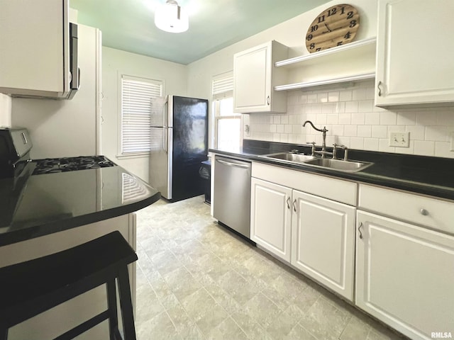 1130 53rd St, Moline, IL 61265 - kitchen with stainless steel appliances, dark countertops, decorative backsplash, and white cabinetry