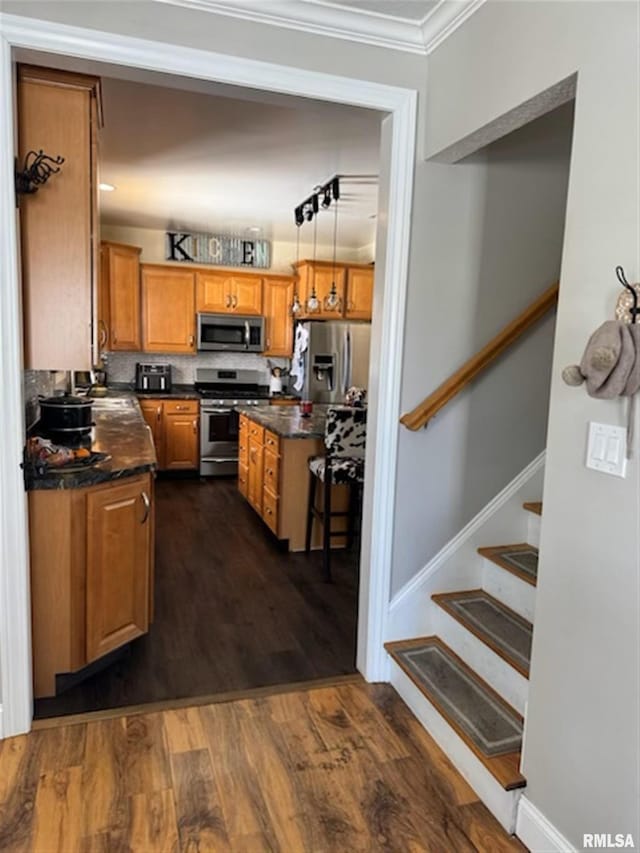 3119 15th St Unit C, Moline, IL 61265 - kitchen with stainless steel appliances, dark countertops, crown molding, brown cabinets, and dark wood-style flooring