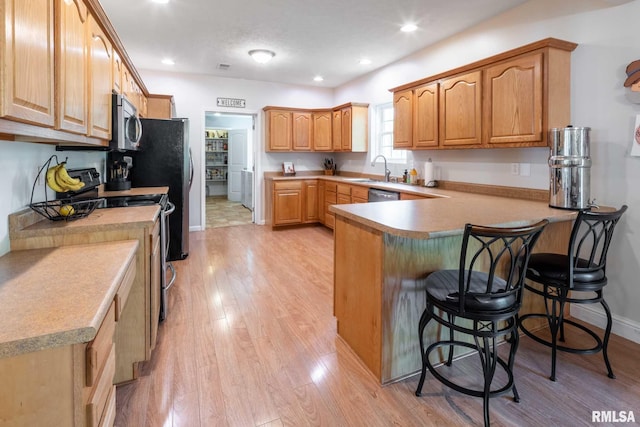 4182 Baptist Camp Rd, Carterville, IL 62918 - kitchen with stainless steel appliances, a peninsula, a kitchen bar, light wood-style flooring, and recessed lighting