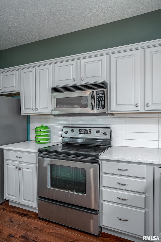 27062 238th St, Le Claire, IA 52753 - kitchen featuring stainless steel appliances, white cabinetry, dark wood finished floors, tasteful backsplash, and a textured ceiling
