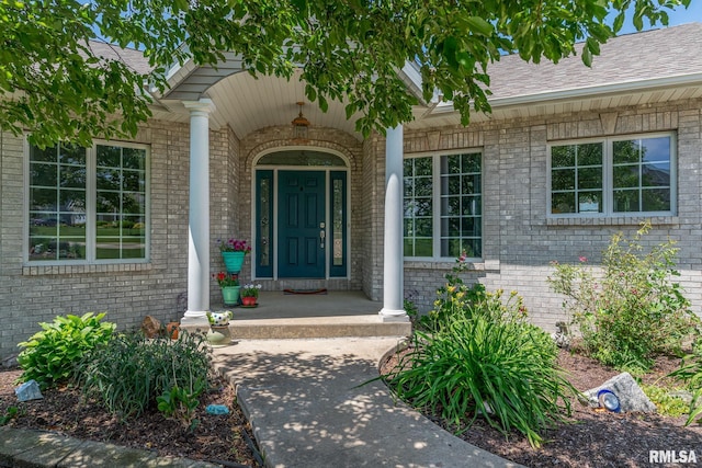 27062 238th St, Le Claire, IA 52753 - view of exterior entry featuring brick siding, covered porch, and roof with shingles