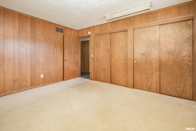 1427 35th Ave, Rock Island, IL 61201 - unfurnished bedroom featuring two closets, carpet flooring, and wood walls