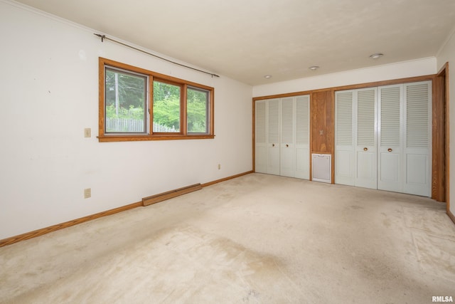 1427 35th Ave, Rock Island, IL 61201 - unfurnished bedroom with baseboard heating, carpet floors, ornamental molding, and multiple closets