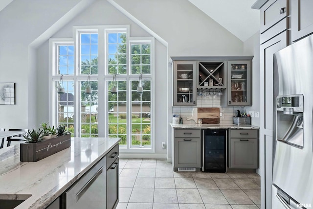 21945 Great River Rd, Le Claire, IA 52753 - indoor wet bar with stainless steel fridge, wine cooler, decorative backsplash, plenty of natural light, and high vaulted ceiling