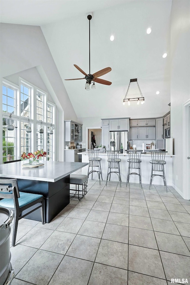 21945 Great River Rd, Le Claire, IA 52753 - dining space featuring light tile patterned floors, a ceiling fan, high vaulted ceiling, and recessed lighting