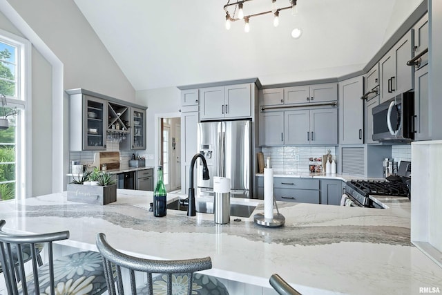 21945 Great River Rd, Le Claire, IA 52753 - kitchen with stainless steel appliances, gray cabinets, light stone countertops, decorative backsplash, and glass insert cabinets