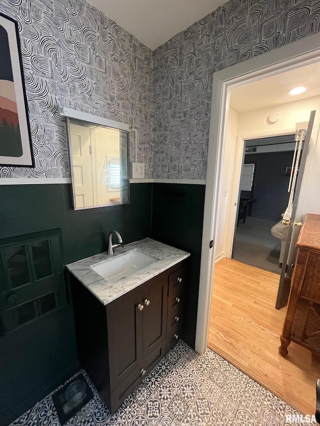 224 S Henderson St, Toulon, IL 61483 - bathroom with wallpapered walls, a wainscoted wall, vanity, and wood finished floors