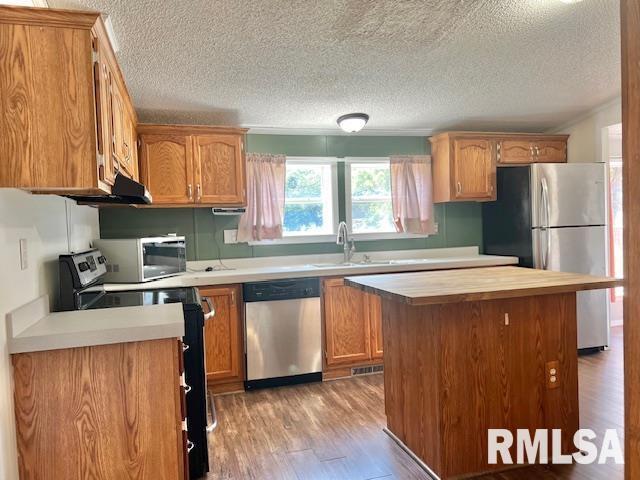 911 4th St, New Boston, IL 61272 - kitchen featuring stainless steel appliances, light wood-style floors, a textured ceiling, brown cabinetry, and a center island