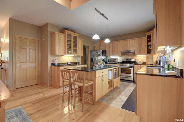 4581 180th St, Clinton, IA 52732 - kitchen with stainless steel appliances, under cabinet range hood, a kitchen island, light brown cabinets, and a kitchen breakfast bar
