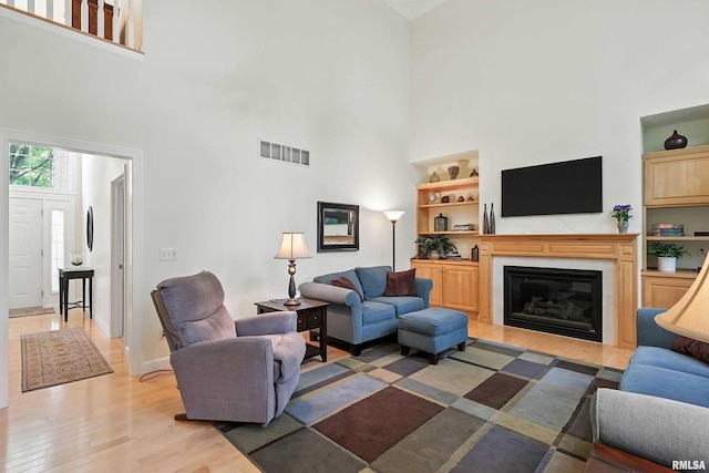 905 Bridgeview Place, Le Claire, IA 52753 - living area featuring a high ceiling, light wood-type flooring, and a glass covered fireplace