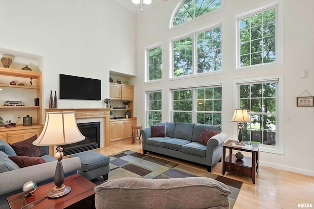 905 Bridgeview Place, Le Claire, IA 52753 - living area featuring a towering ceiling, light wood-style floors, a glass covered fireplace, and built in shelves