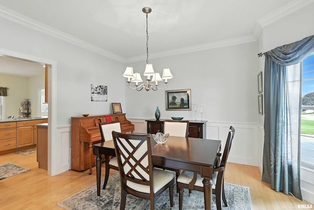 905 Bridgeview Place, Le Claire, IA 52753 - dining area featuring crown molding, light wood-style floors, a chandelier, wainscoting, and a decorative wall