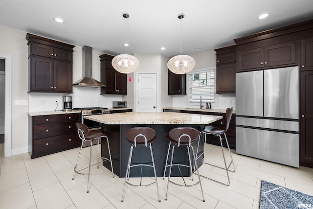 5727 Charlie Chase Ln, Bettendorf, IA 52722 - kitchen with stainless steel appliances, wall chimney exhaust hood, a kitchen breakfast bar, dark brown cabinetry, and recessed lighting
