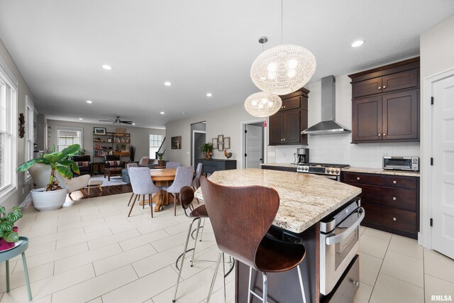 5727 Charlie Chase Ln, Bettendorf, IA 52722 - kitchen featuring wall chimney range hood, dark brown cabinetry, a kitchen island, a chandelier, and recessed lighting
