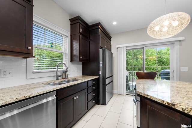 5727 Charlie Chase Ln, Bettendorf, IA 52722 - kitchen with appliances with stainless steel finishes, decorative backsplash, a chandelier, light stone counters, and dark brown cabinets
