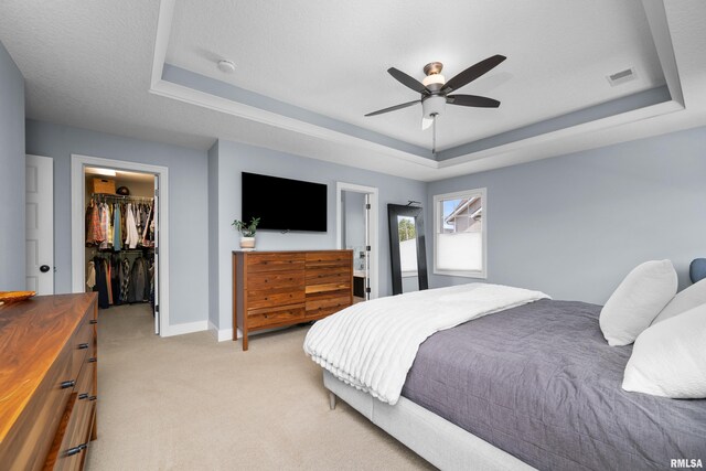 5727 Charlie Chase Ln, Bettendorf, IA 52722 - bedroom featuring a tray ceiling, light colored carpet, a walk in closet, a closet, and ceiling fan
