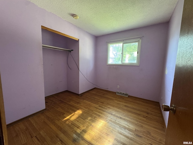 2938 Summit Hills Ct, Bettendorf, IA 52722 - unfurnished bedroom with wood finished floors, a textured ceiling, and a closet