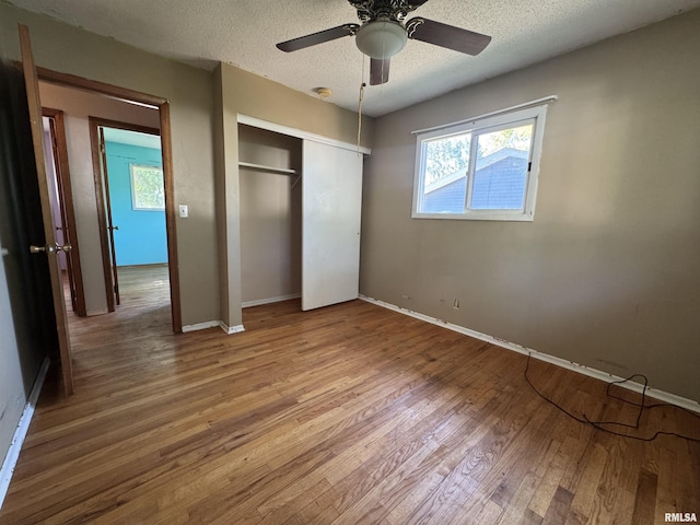 2938 Summit Hills Ct, Bettendorf, IA 52722 - unfurnished bedroom featuring wood finished floors, multiple windows, a closet, a textured ceiling, and a ceiling fan