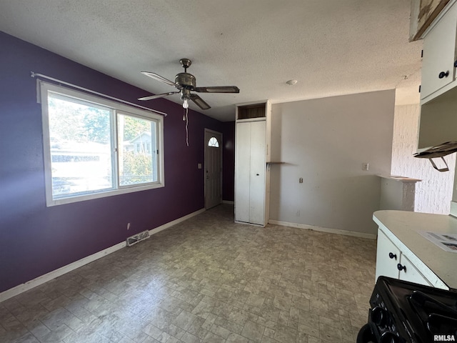 2938 Summit Hills Ct, Bettendorf, IA 52722 - kitchen with white cabinetry, ceiling fan, black gas stove, and a textured ceiling