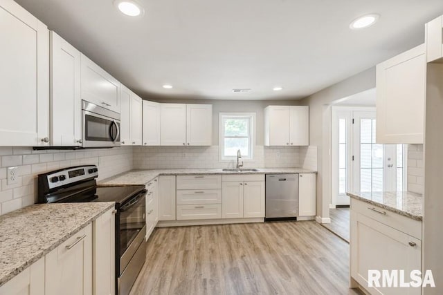 1231 Devils Glen Rd, Bettendorf, IA 52722 - kitchen with appliances with stainless steel finishes, light wood-style flooring, backsplash, recessed lighting, and white cabinets