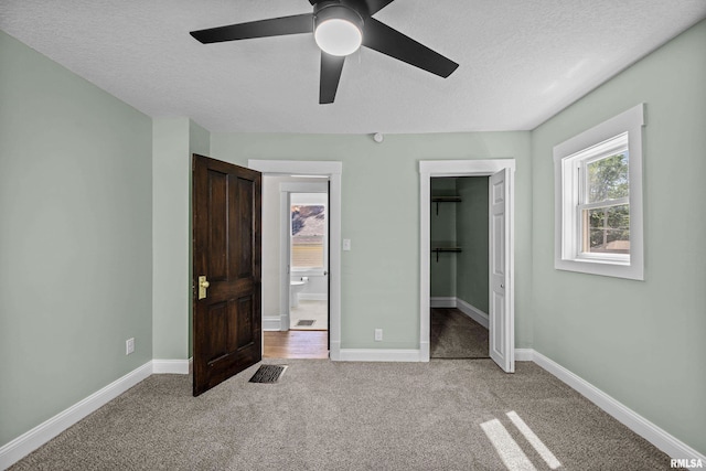 2664 Fair Ave, Davenport, IA 52803 - unfurnished bedroom featuring light colored carpet, a textured ceiling, a spacious closet, ensuite bathroom, and ceiling fan