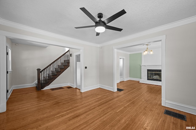 2664 Fair Ave, Davenport, IA 52803 - unfurnished living room featuring stairway, a ceiling fan, light wood-style floors, ornamental molding, and a textured ceiling