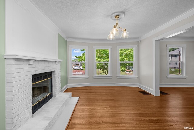 2664 Fair Ave, Davenport, IA 52803 - unfurnished living room featuring wood finished floors, a brick fireplace, plenty of natural light, a textured ceiling, and crown molding