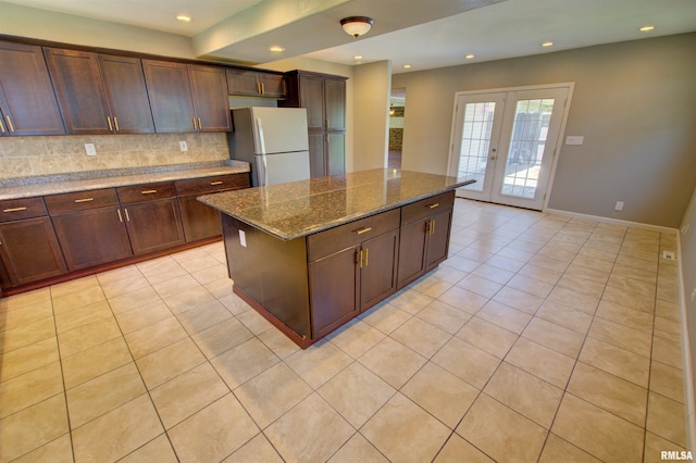 1008 5th Ave, Camanche, IA 52730 - kitchen with freestanding refrigerator, light tile patterned floors, decorative backsplash, french doors, and dark stone counters