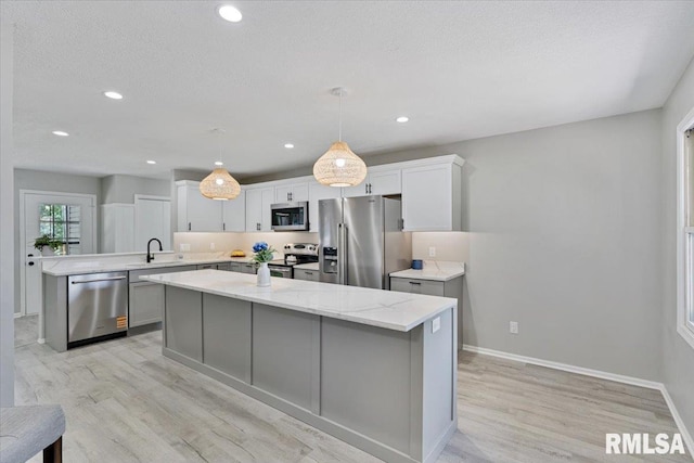 4050 4th St Unit B, East Moline, IL 61244 - kitchen featuring stainless steel appliances, light wood-style flooring, a center island, white cabinetry, and a peninsula