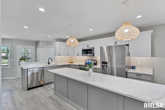 4050 4th St Unit B, East Moline, IL 61244 - kitchen with appliances with stainless steel finishes, a peninsula, light wood-style flooring, light stone counters, and decorative light fixtures