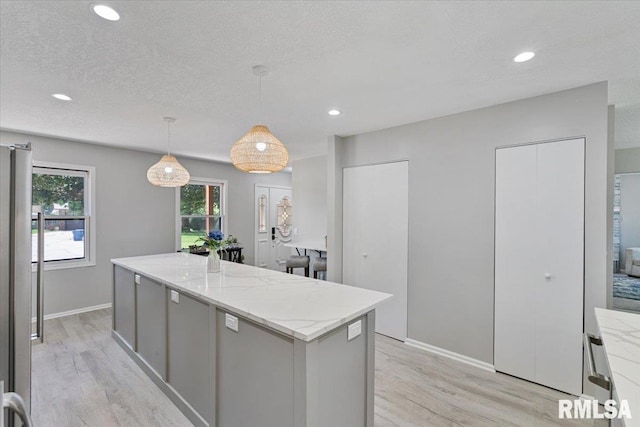 4050 4th St Unit B, East Moline, IL 61244 - kitchen featuring light wood finished floors, healthy amount of natural light, a center island, recessed lighting, and a textured ceiling