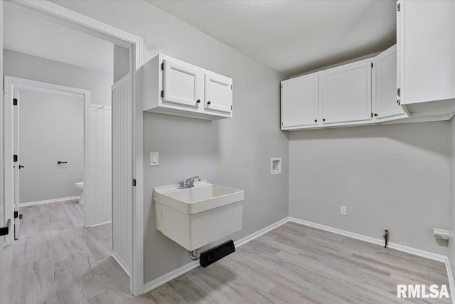 4050 4th St Unit B, East Moline, IL 61244 - laundry area with washer hookup, light wood-style flooring, a textured ceiling, and cabinet space