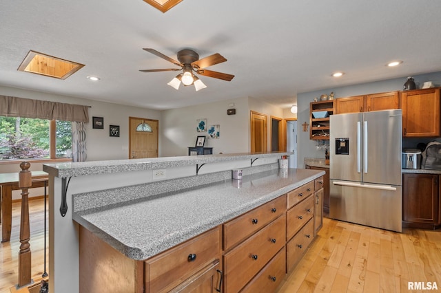910 Fyre Lake Dr, Sherrard, IL 61281 - kitchen with stainless steel refrigerator with ice dispenser, light wood-style floors, a kitchen island, ceiling fan, and brown cabinets