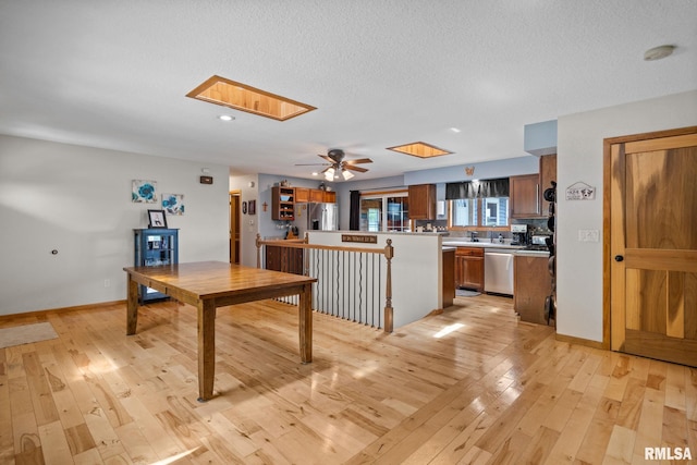 910 Fyre Lake Dr, Sherrard, IL 61281 - kitchen featuring appliances with stainless steel finishes, light wood-style flooring, light countertops, a skylight, and brown cabinets