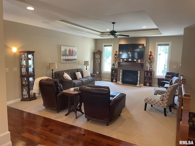 1175 Rustic View Ct, Eldridge, IA 52748 - carpeted living room with a raised ceiling, wood finished floors, a ceiling fan, a glass covered fireplace, and recessed lighting