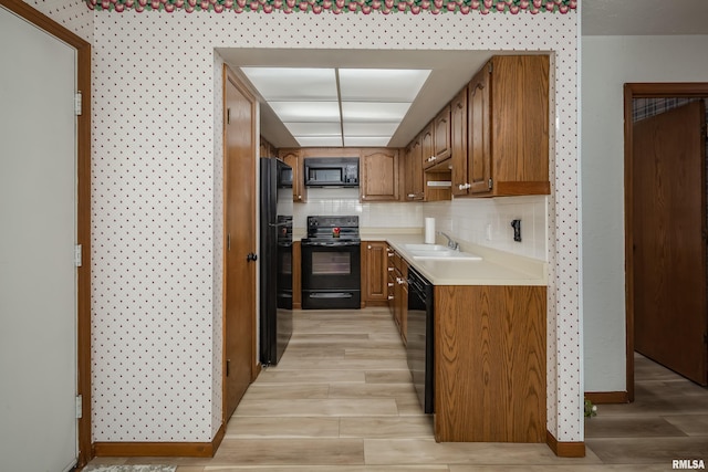 4554 Bunker Hill Dr, Bettendorf, IA 52722 - kitchen with black appliances, light wood-style floors, light countertops, brown cabinetry, and decorative backsplash
