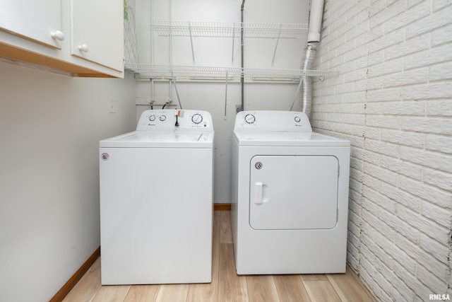 4554 Bunker Hill Dr, Bettendorf, IA 52722 - laundry room featuring washing machine and dryer, cabinet space, and light wood-style flooring