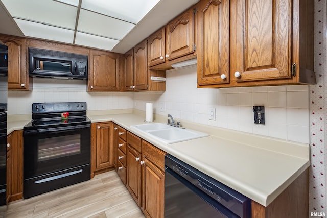 4554 Bunker Hill Dr, Bettendorf, IA 52722 - kitchen with black appliances, brown cabinetry, and light wood finished floors