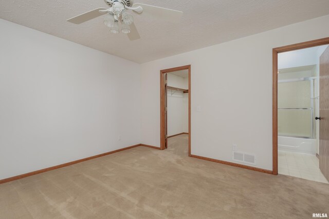 4554 Bunker Hill Dr, Bettendorf, IA 52722 - unfurnished bedroom featuring light carpet, a textured ceiling, a walk in closet, a closet, and ensuite bath