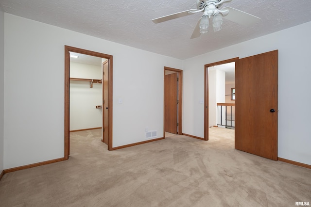 4554 Bunker Hill Dr, Bettendorf, IA 52722 - unfurnished bedroom featuring carpet, a walk in closet, a closet, a ceiling fan, and a textured ceiling
