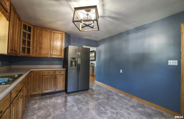 1221 4th St, Camanche, IA 52730 - kitchen with stainless steel fridge, brown cabinets, glass insert cabinets, and a chandelier