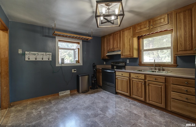 1221 4th St, Camanche, IA 52730 - kitchen with stainless steel electric range oven, brown cabinets, and under cabinet range hood