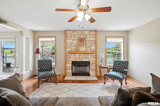 106 Valley View Dr, Sherrard, IL 61281 - living area featuring wood finished floors, a stone fireplace, and a ceiling fan