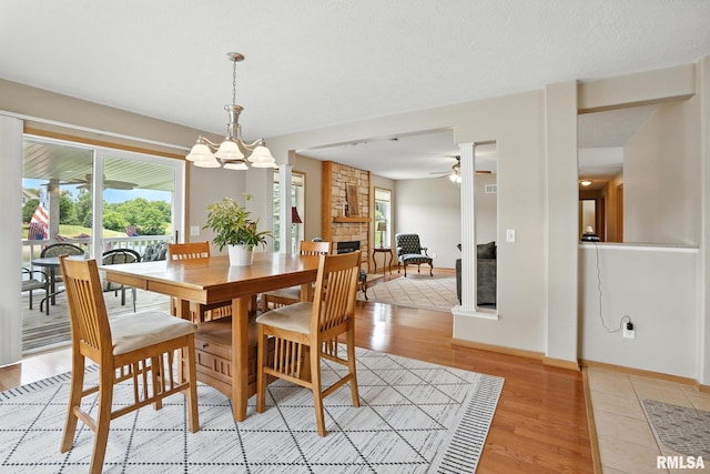 106 Valley View Dr, Sherrard, IL 61281 - dining space featuring a fireplace, a ceiling fan, light wood finished floors, and a chandelier